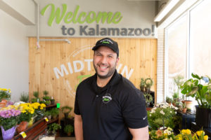 Midtown Fresh Market owner in front of fresh flowers and welcome sign