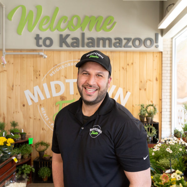 Midtown Fresh Market owner in front of fresh flowers and welcome sign
