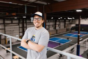 Picture of Dan McConnon, All in Pickleball Gym's owner standing in front of the pickleball courts.