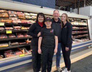 Z’s Hometown Market family photo in front of the meat section of their store